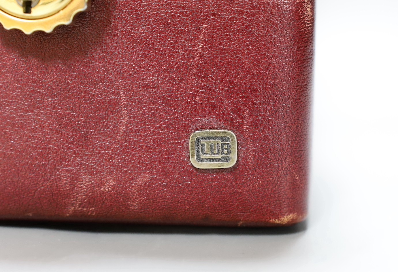 A small red leather mounted suitcase